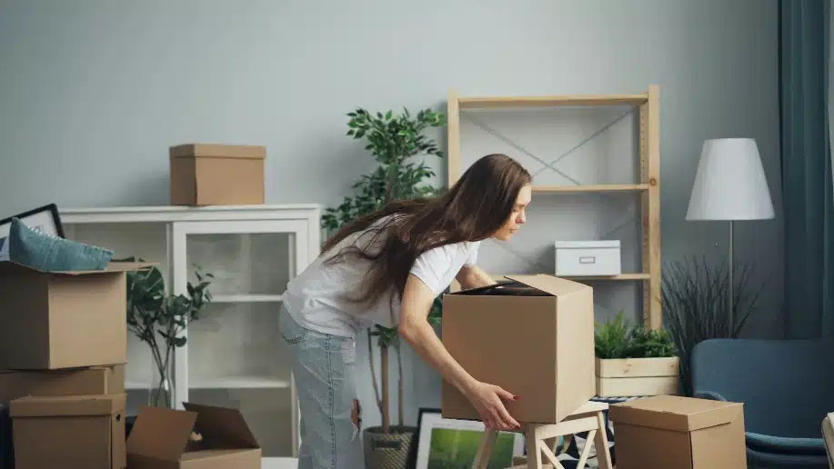 a woman moving boxes in a living room