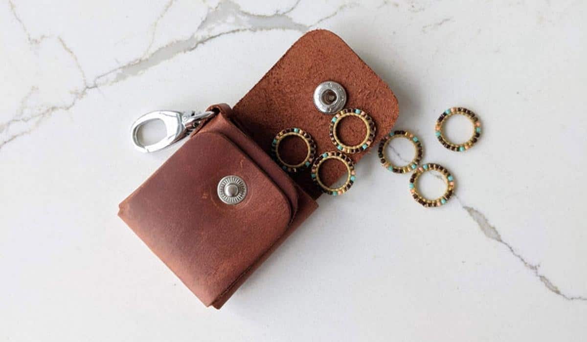 Leather pouch containing colorful beaded stitch markers for knitting