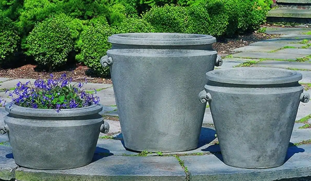 Three grey concrete garden planters on a stone patio