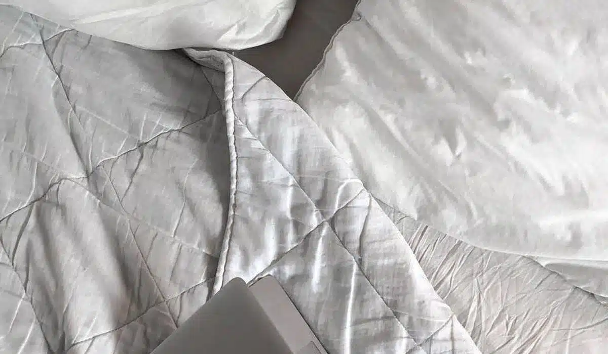 Laptop on white quilted bedding for a cozy workspace