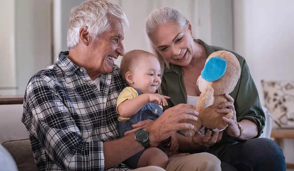 Grandparents showing a stuffed toy to their smiling grandson