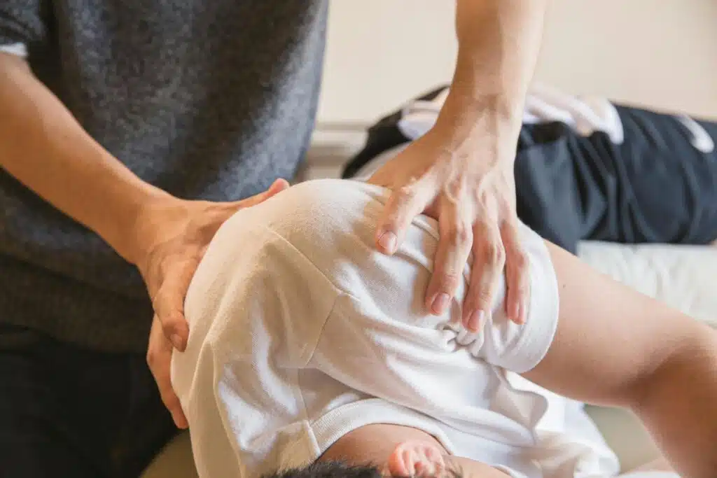 A massage therapist massaging the shoulders of a patient.