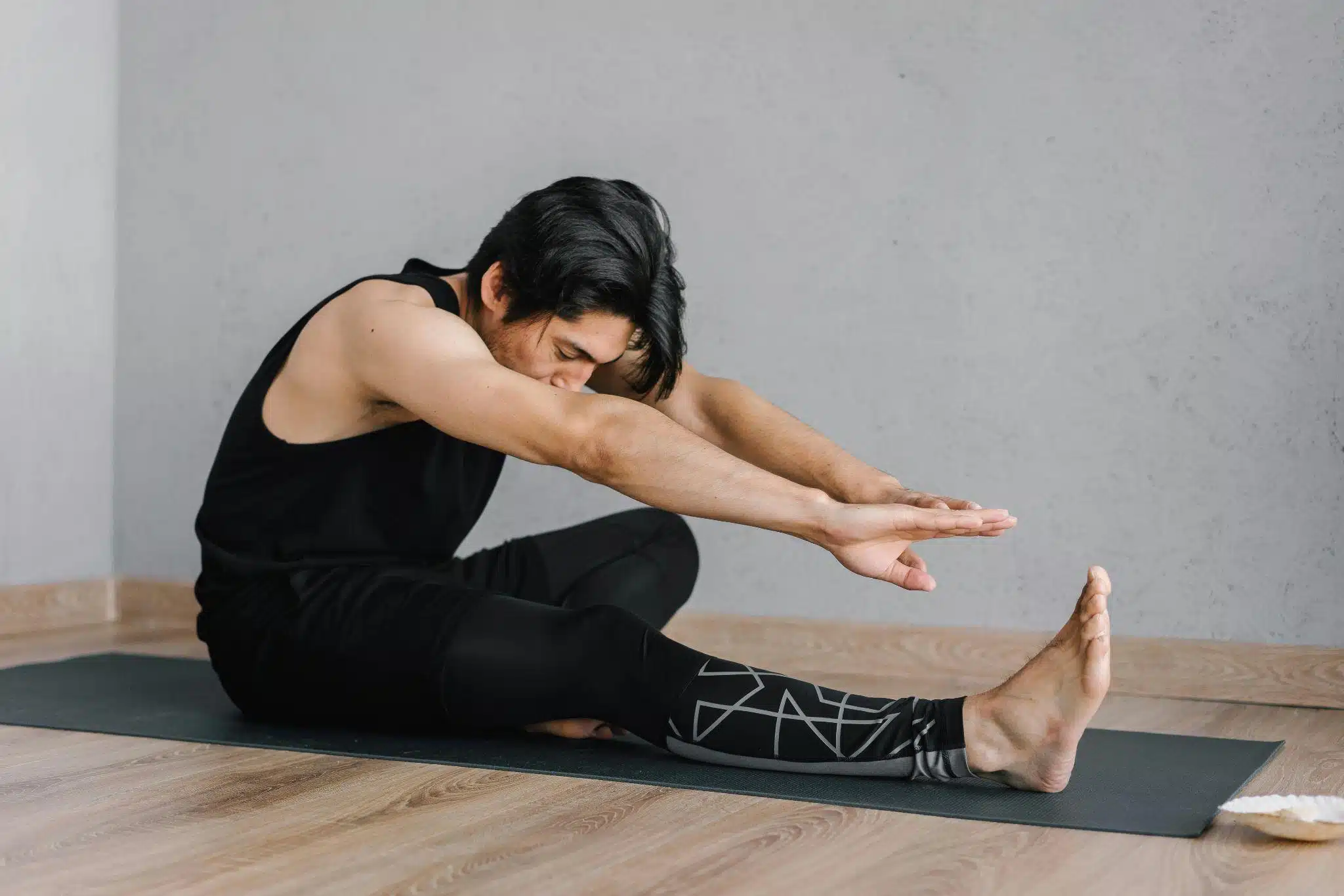 A man stretching on the floor with a mat.