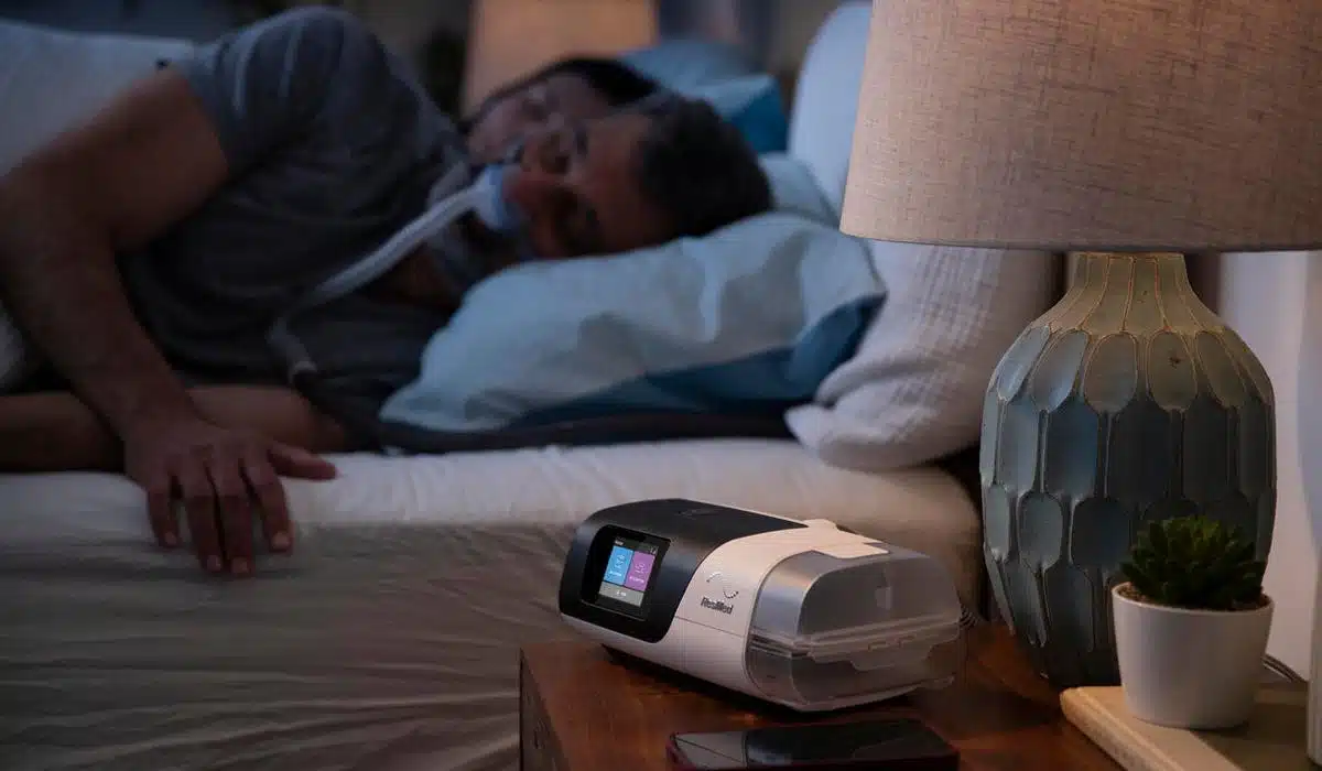 Man sleeping with CPAP machine on bedside table