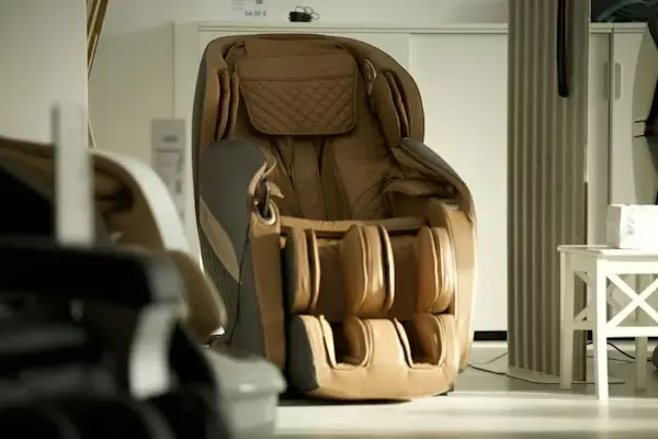 Tan leather massage chair in a well-lit showroom next to a white side table