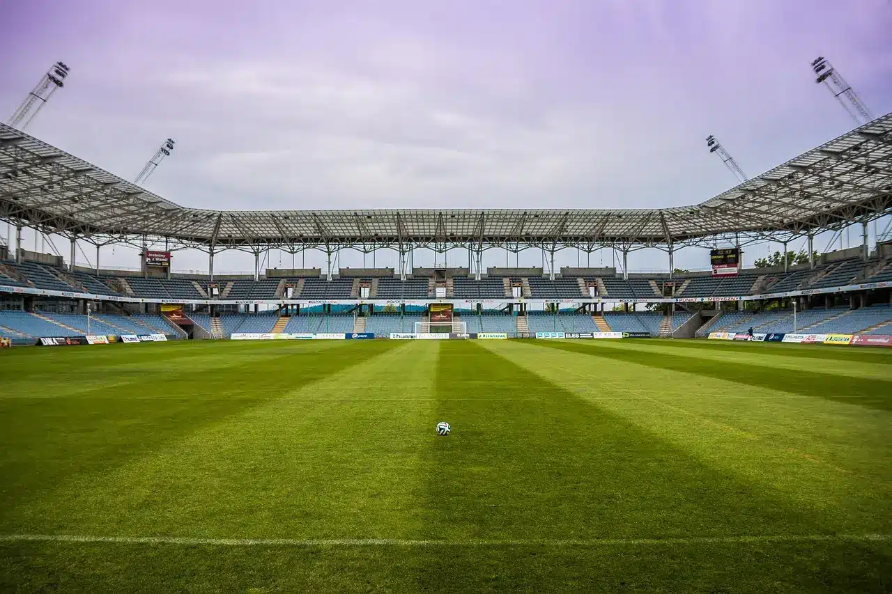 Soccer ball on empty green field in large stadium under cloudy sky
