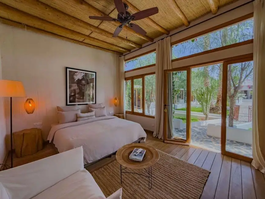 Cozy bedroom with large windows, wooden ceiling, and neutral decor in a serene setting