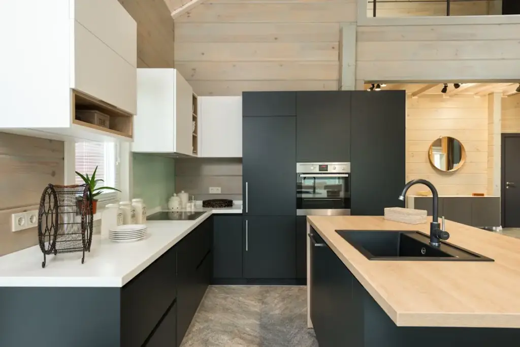 Modern kitchen with sleek black cabinetry, integrated oven, wooden countertops, and light wood walls