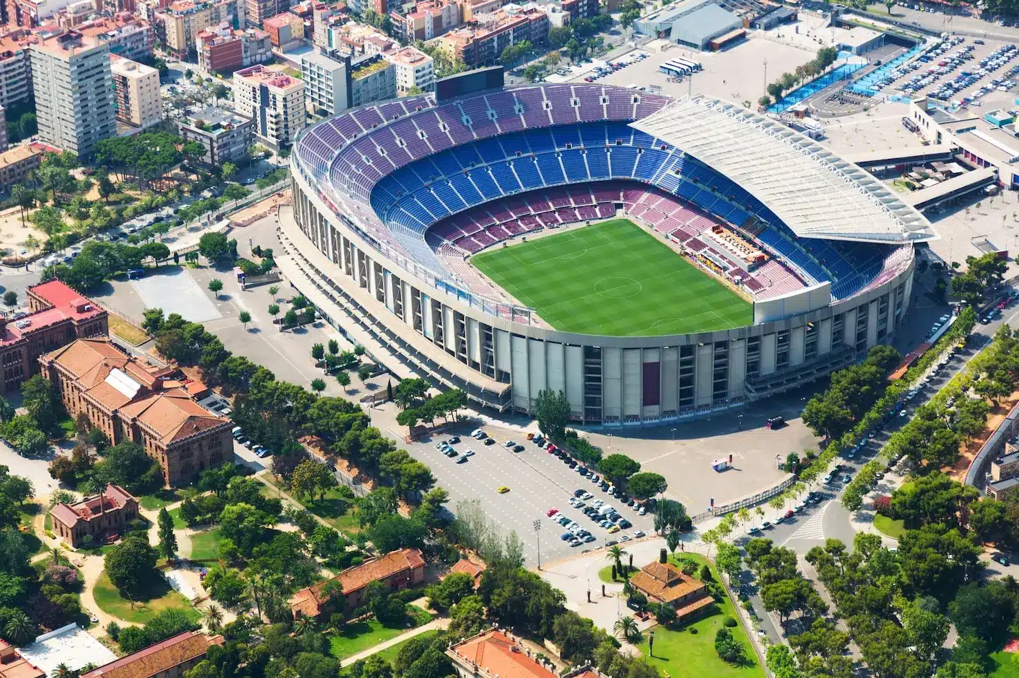 Aerial view of large football stadium surrounded by urban buildings and green park areas