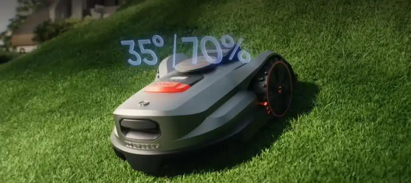 Robotic lawn mower on a grassy slope in bright outdoor setting