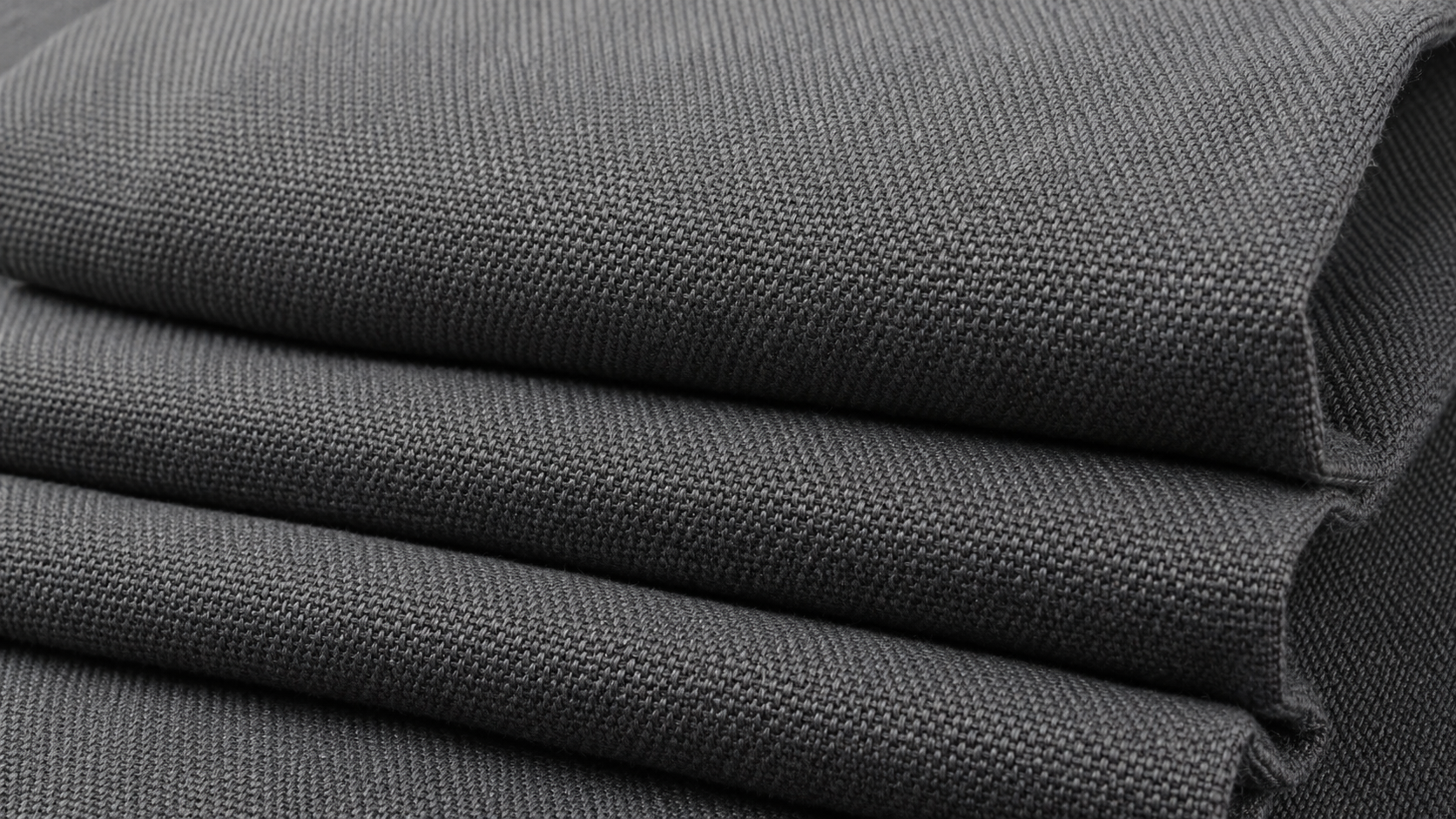 Close-up of charcoal triple-weave blackout curtain fabric showing dense texture and thick folds.