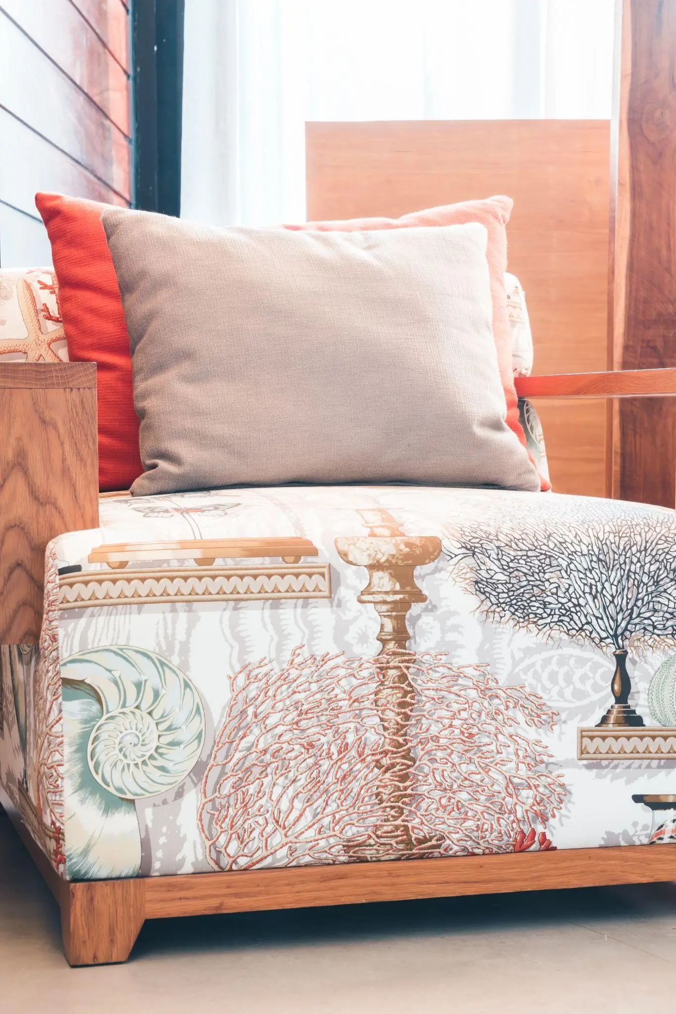 Patterned armchair with gray and orange cushions in a bright, modern indoor setting