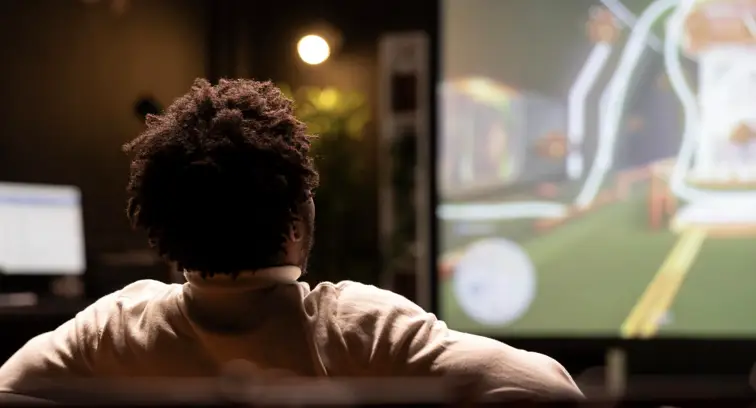 Person sitting in dimly lit room watching screen with blurred visuals