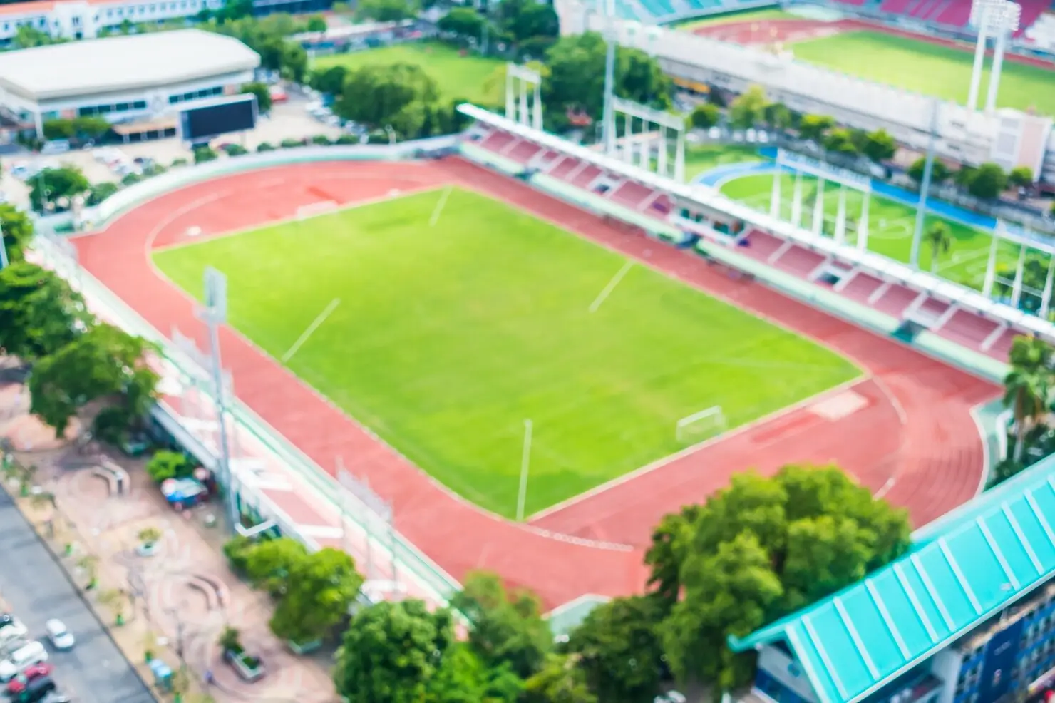 Blurred view of large outdoor stadium with green field and red running track