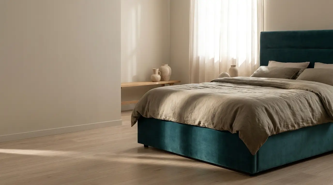 Teal upholstered bed with beige linens in minimalist bedroom with natural light