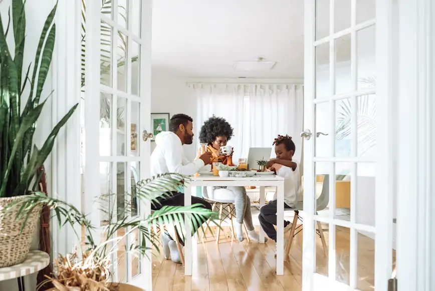 Family enjoying breakfast around a white table in a sunlit dining room