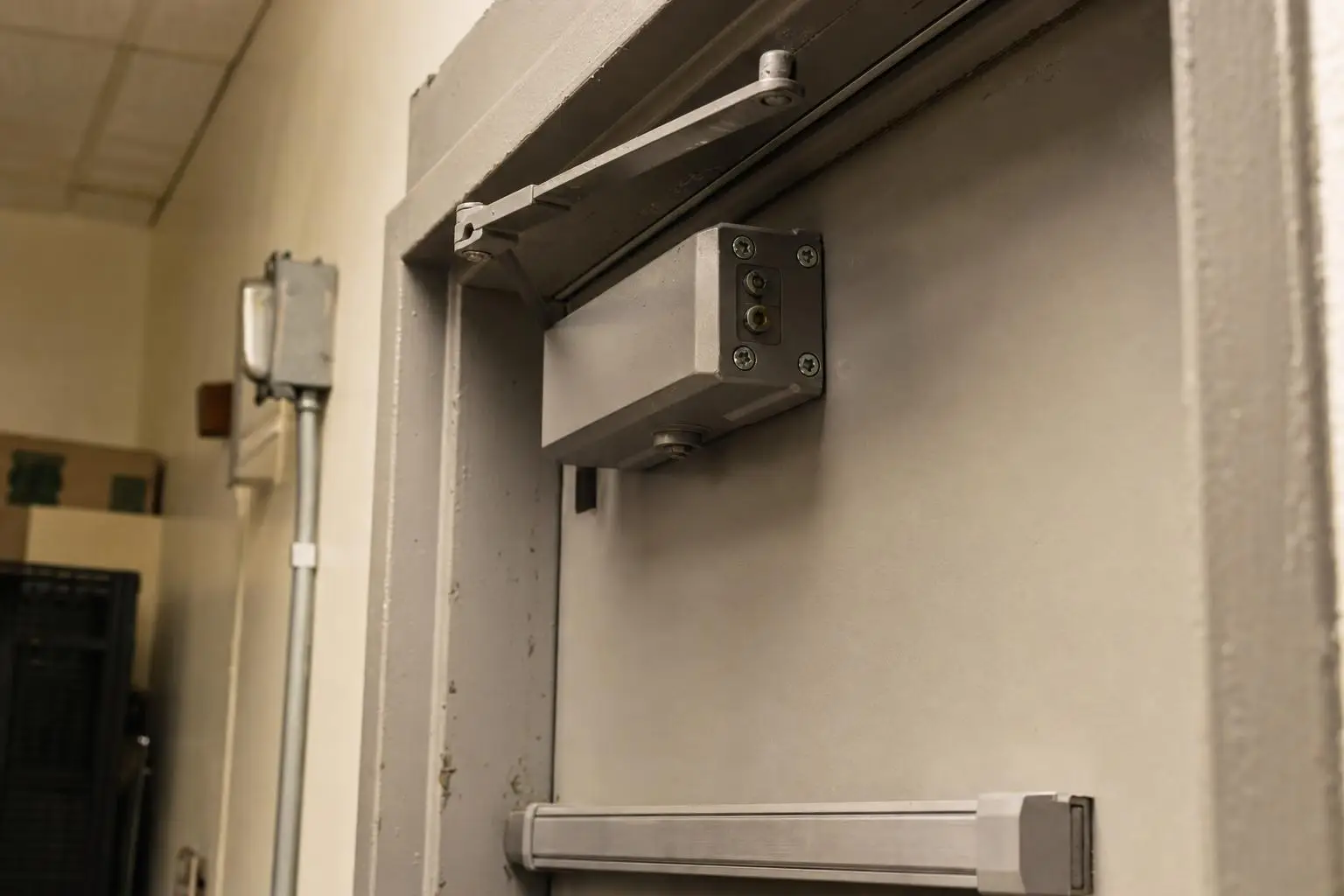 Commercial metal door with hydraulic closer in an industrial hallway setting