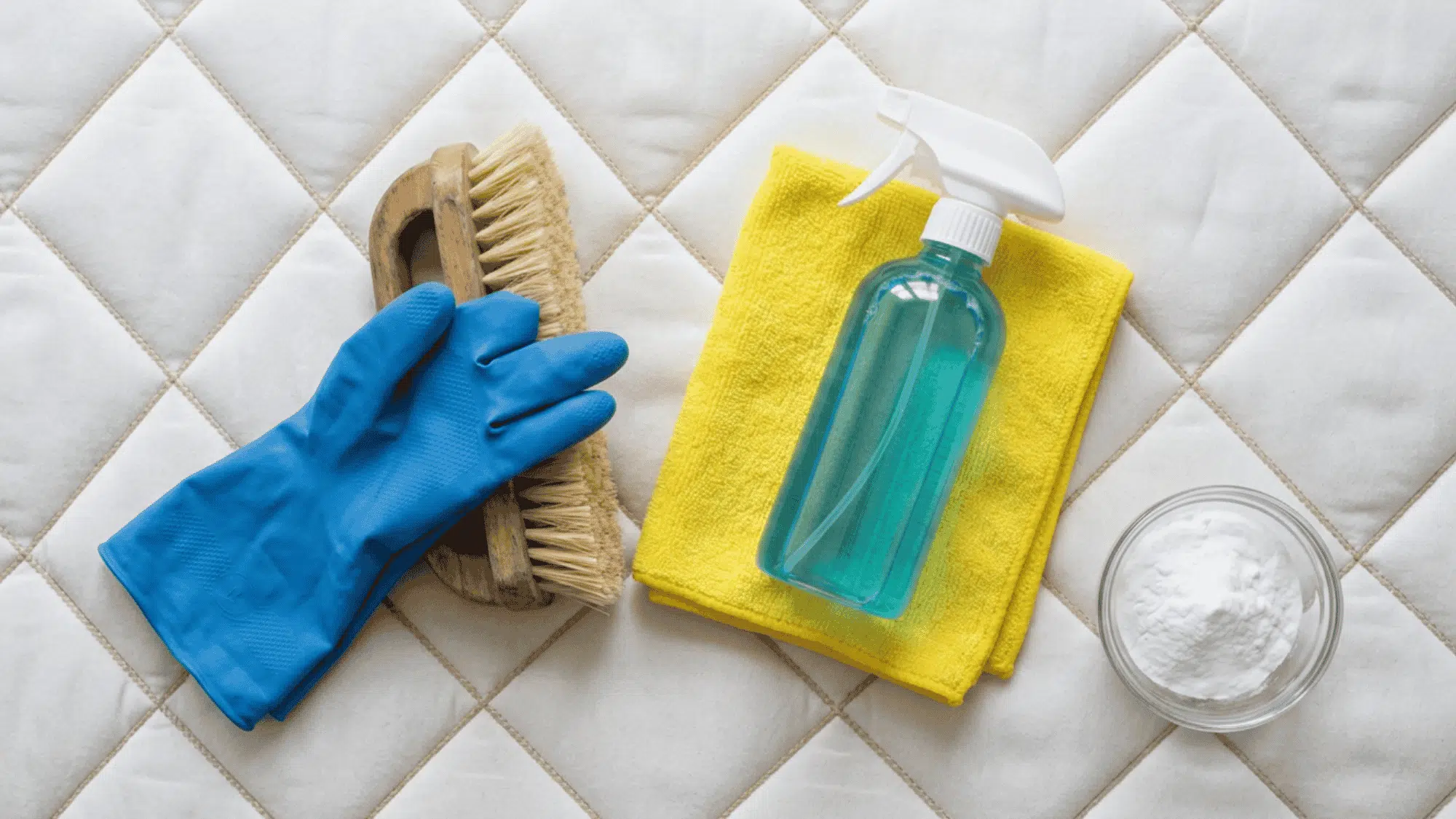 Mattress cleaning supplies with gloves, spray bottle, towel, brush, and baking soda.