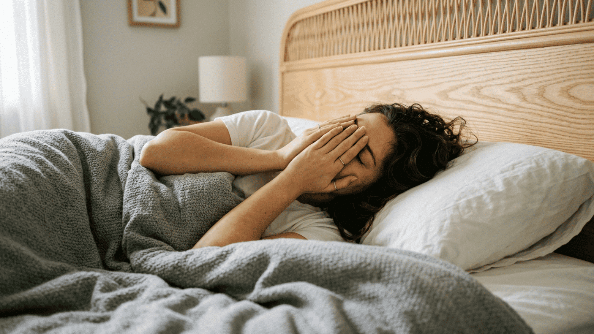 tired woman covering her face in bed after a sleepless night