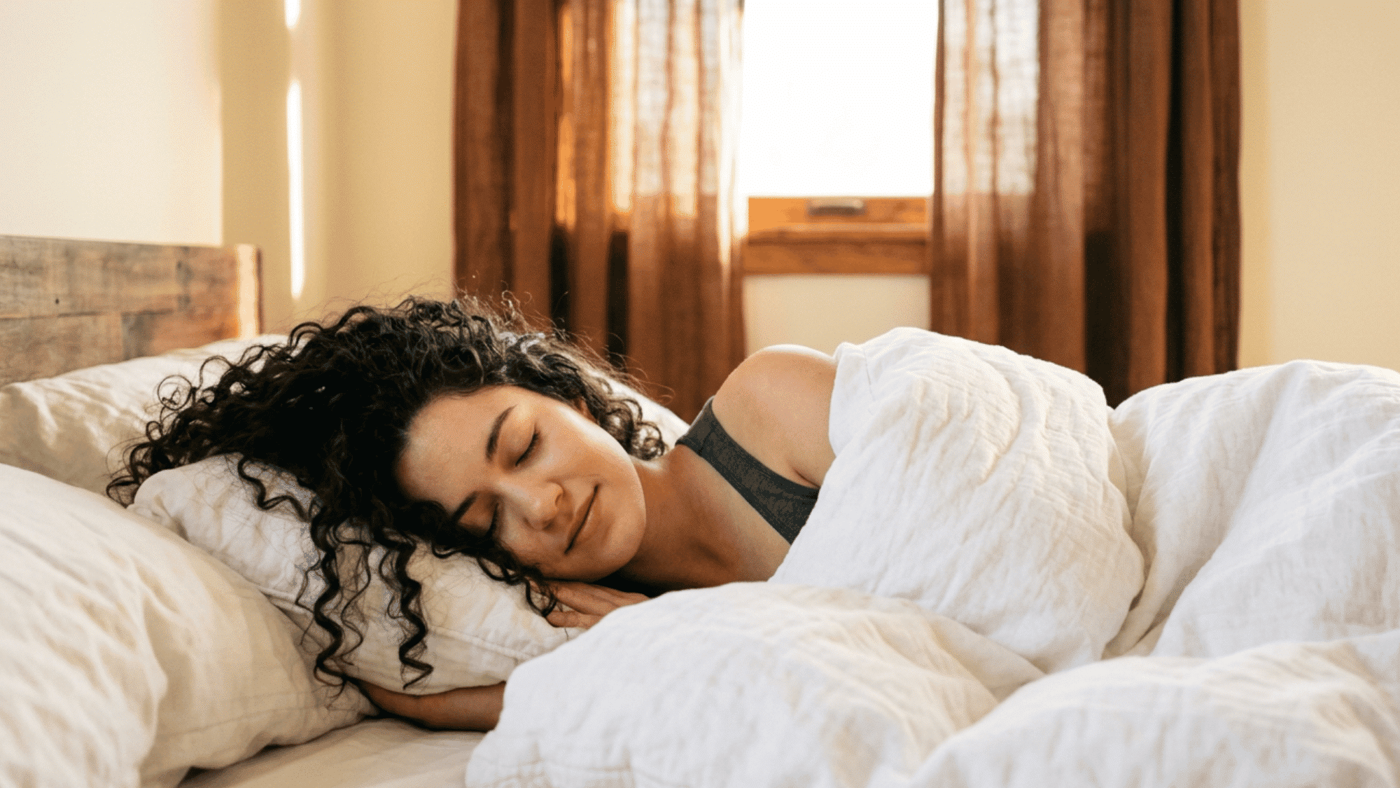 Person sleeping peacefully in a cozy bedroom with soft morning light through the window.