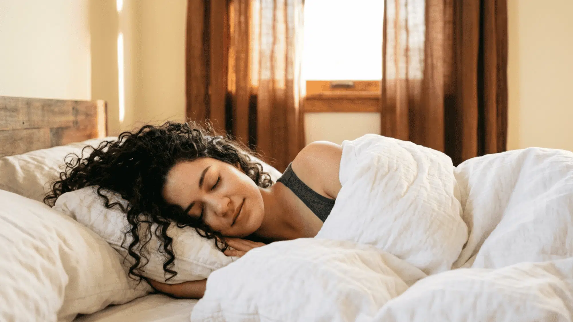 Person sleeping peacefully in a cozy bedroom with soft morning light through the window.