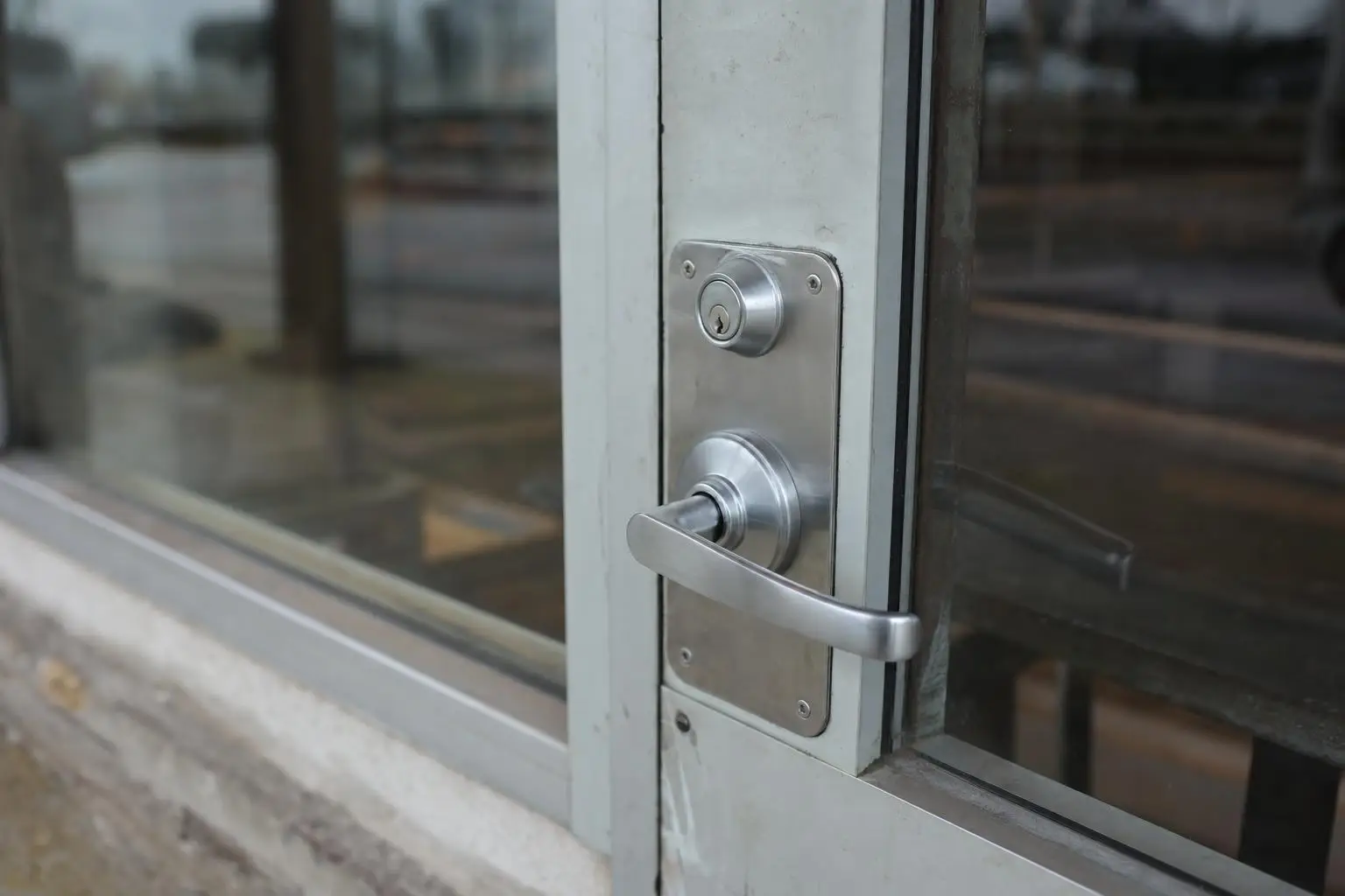 Close-up of metallic door handle and lock on glass door in outdoor setting