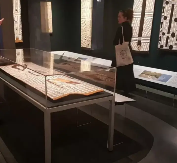 Art exhibition featuring wooden artifacts and patterned art panels under soft lighting