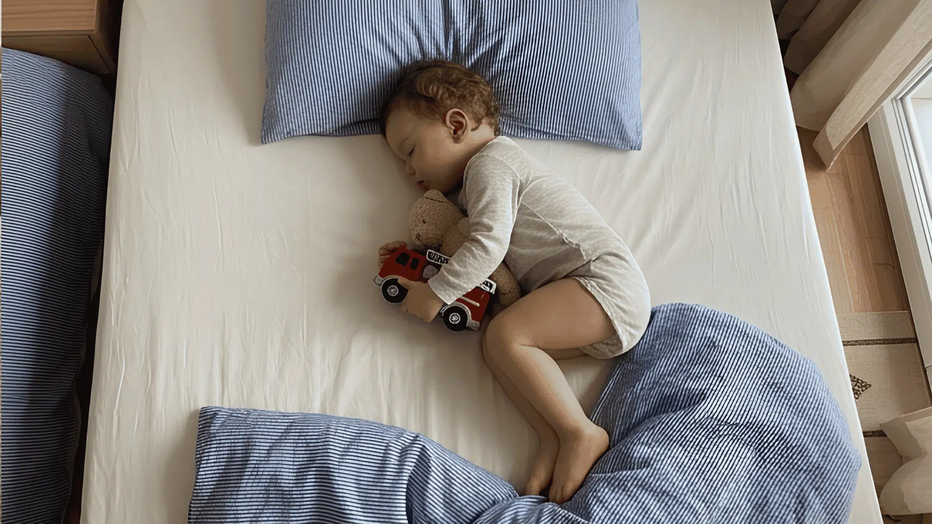 toddler sleeping with toy car and teddy bear during sleep regression