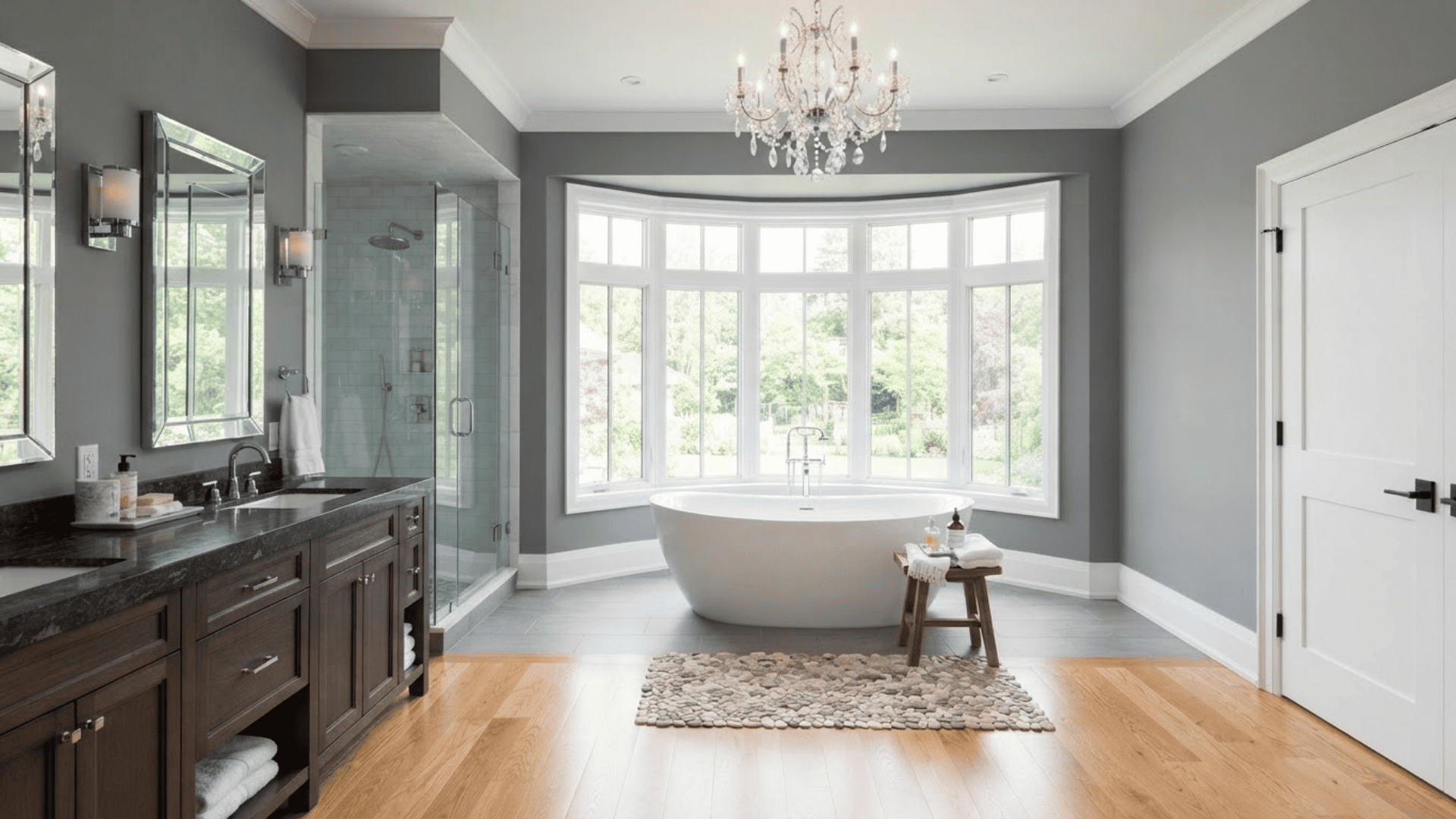 gray bathroom with dark wood vanity, freestanding tub, large windows and white trim