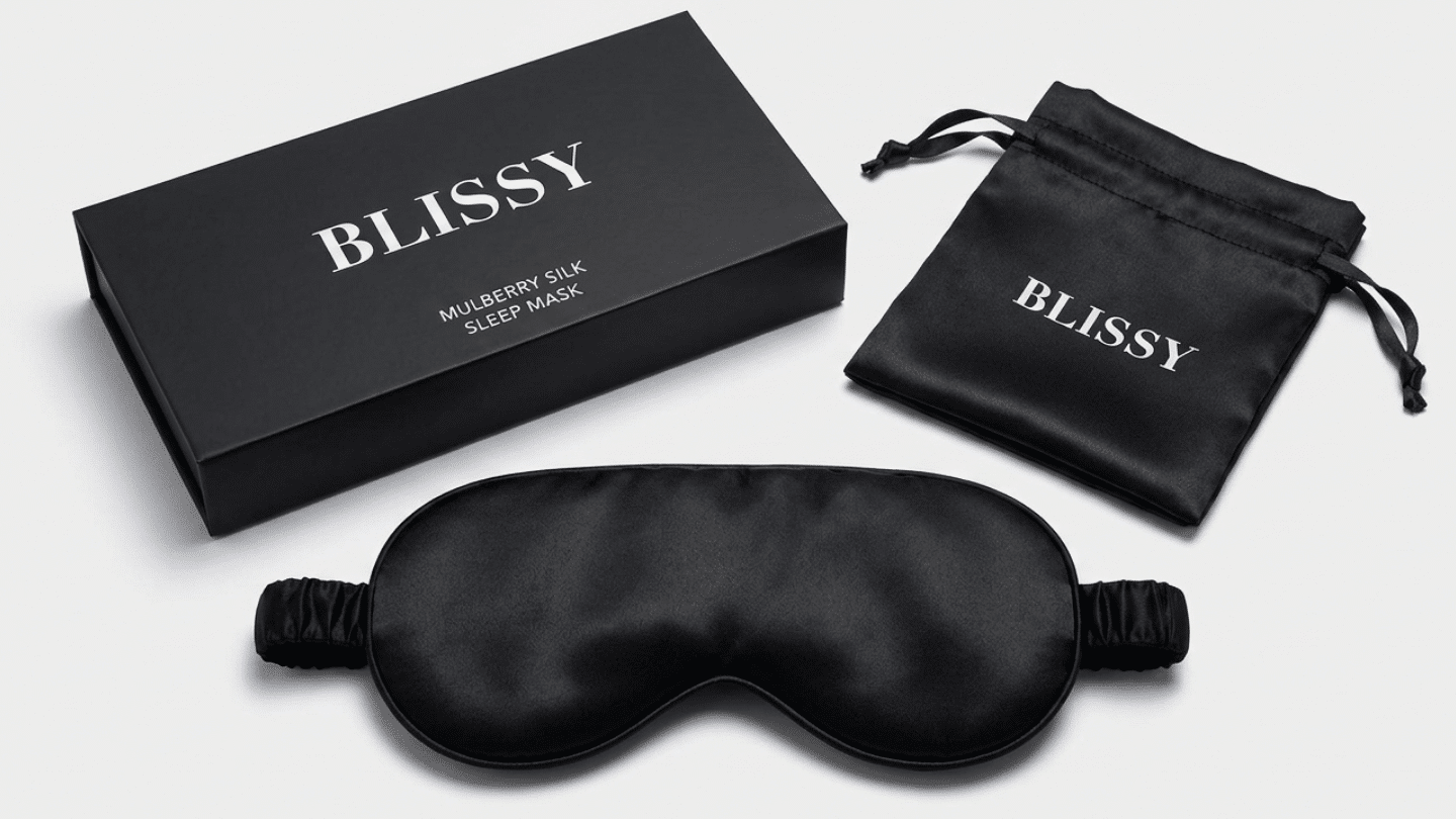 black Blissy silk sleep mask displayed with its matching branded box and drawstring pouch on display