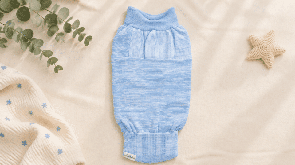 blue swaddelini swaddle displayed flat on a cream background with soft nursery decor