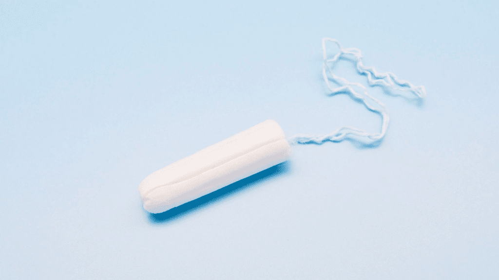 single white tampon with string on a light blue background