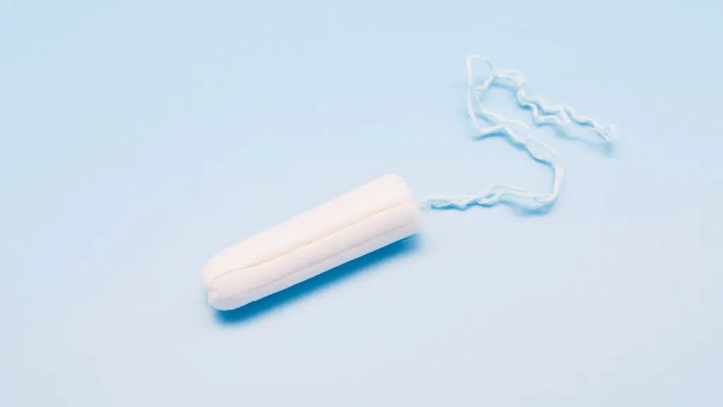 single white tampon with string on a light blue background