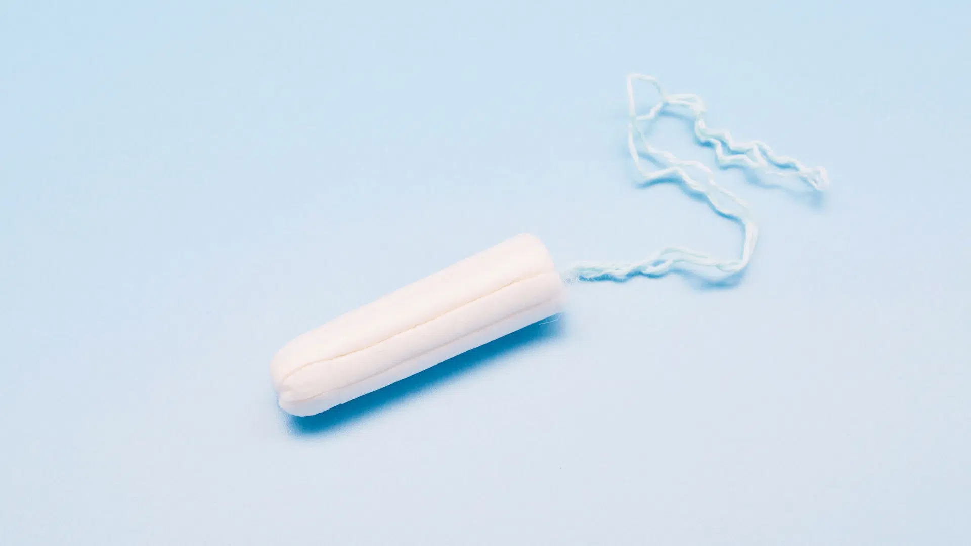single white tampon with string on a light blue background