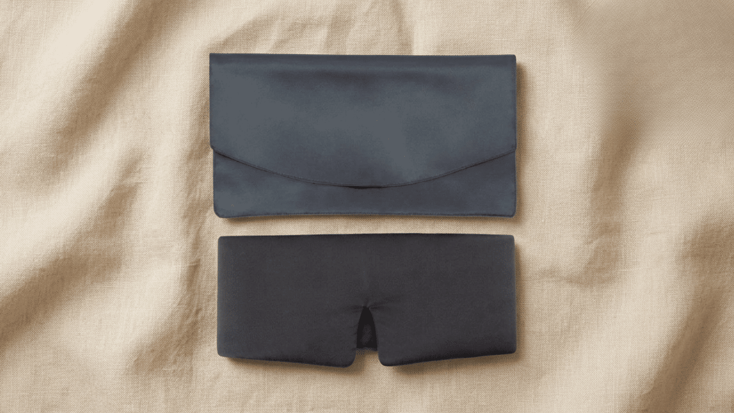 dark Baloo Living weighted sleep mask with matching storage pouch arranged on beige linen background