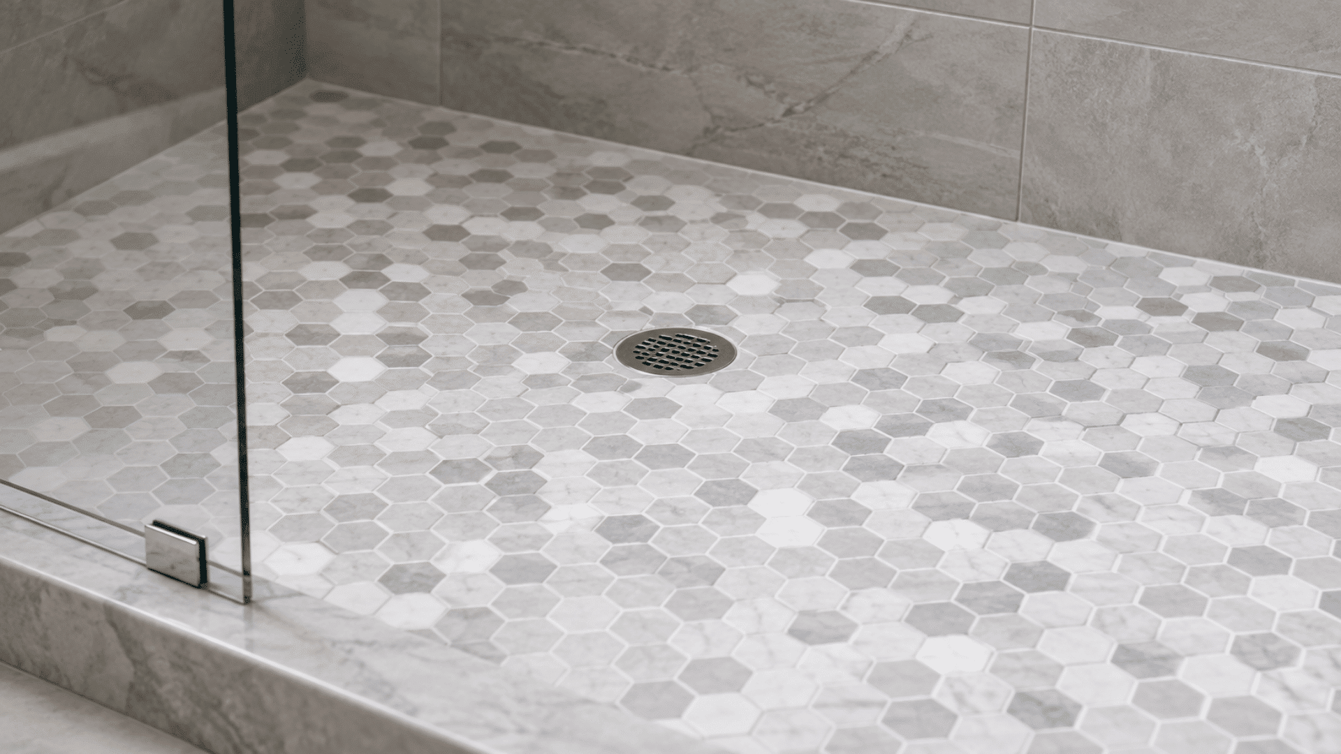 gray and white hexagon mosaic shower floor with round metal drain