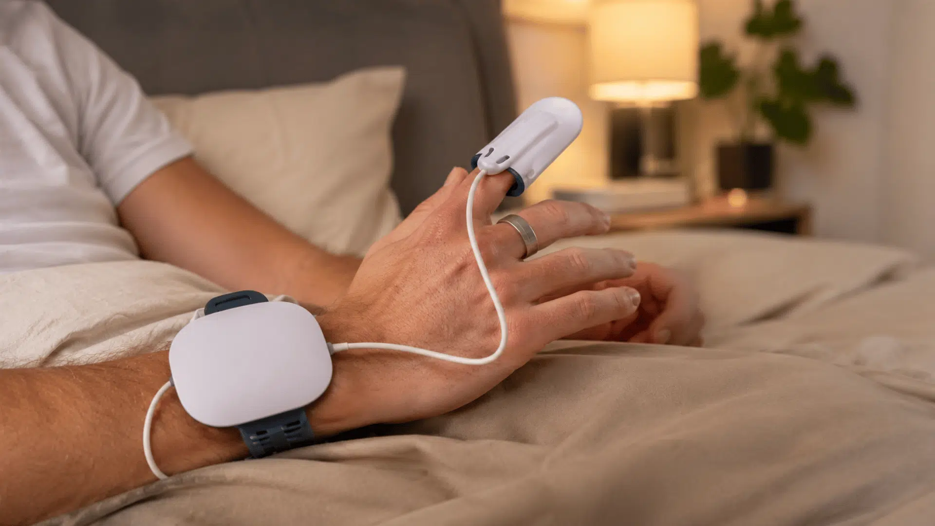 Hand wearing sleep monitoring sensors with finger oxygen monitor during home sleep test