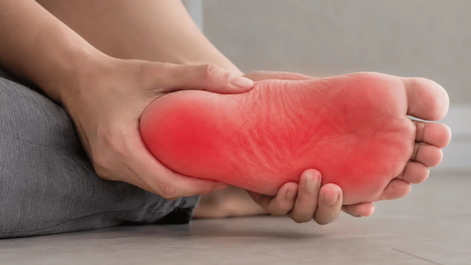 Close-up of a foot on grey bedsheets showing a burning sensation area at night.