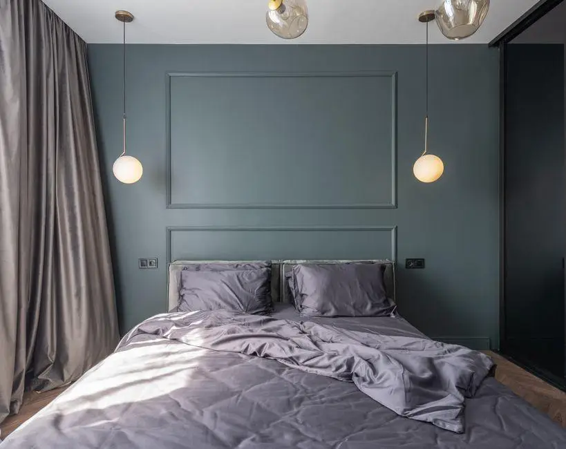 Modern bedroom with gray bedding, green accent wall, hanging pendant lights, and floor-length curtains
