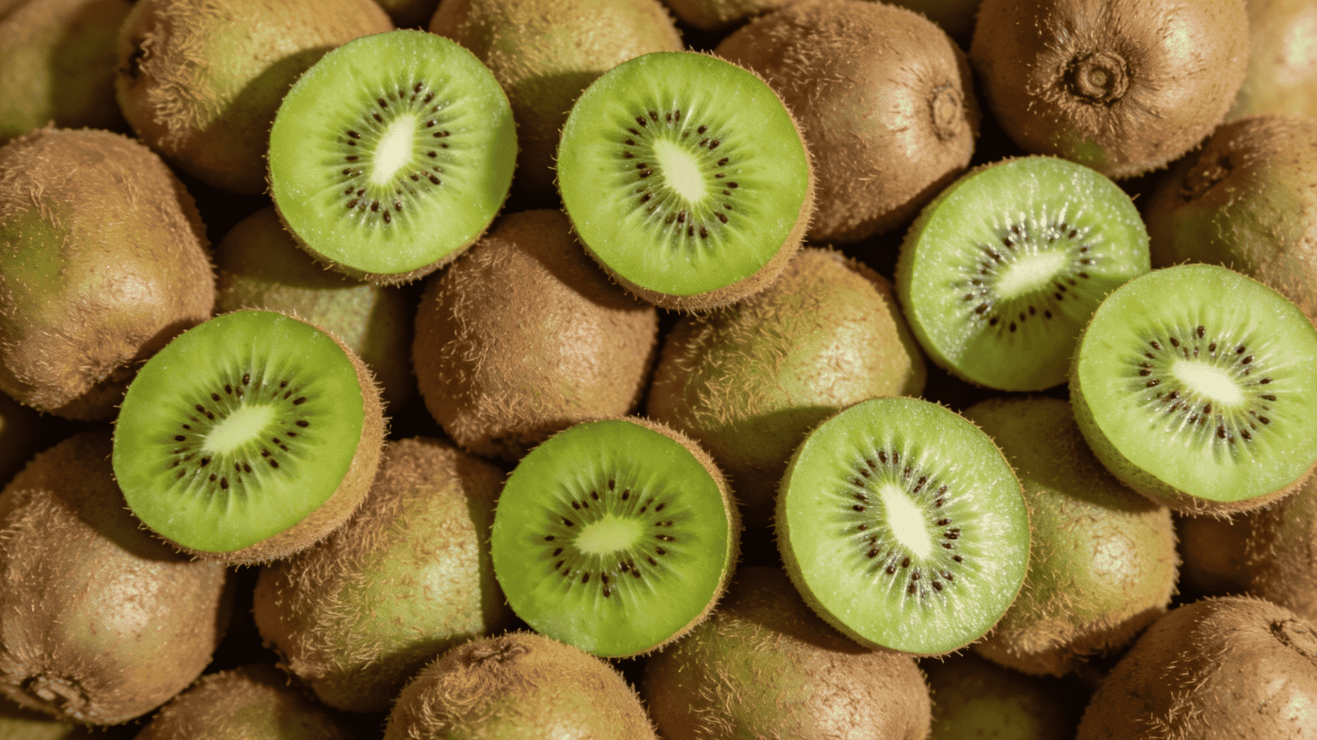 whole and halved kiwifruit showing bright green flesh and tiny black seeds