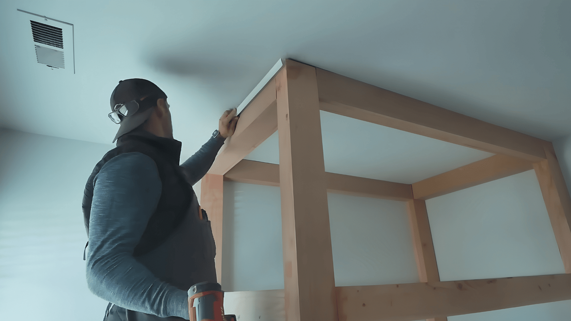 man adding storage sections and wooden supports to a large built-in bunk bed structure