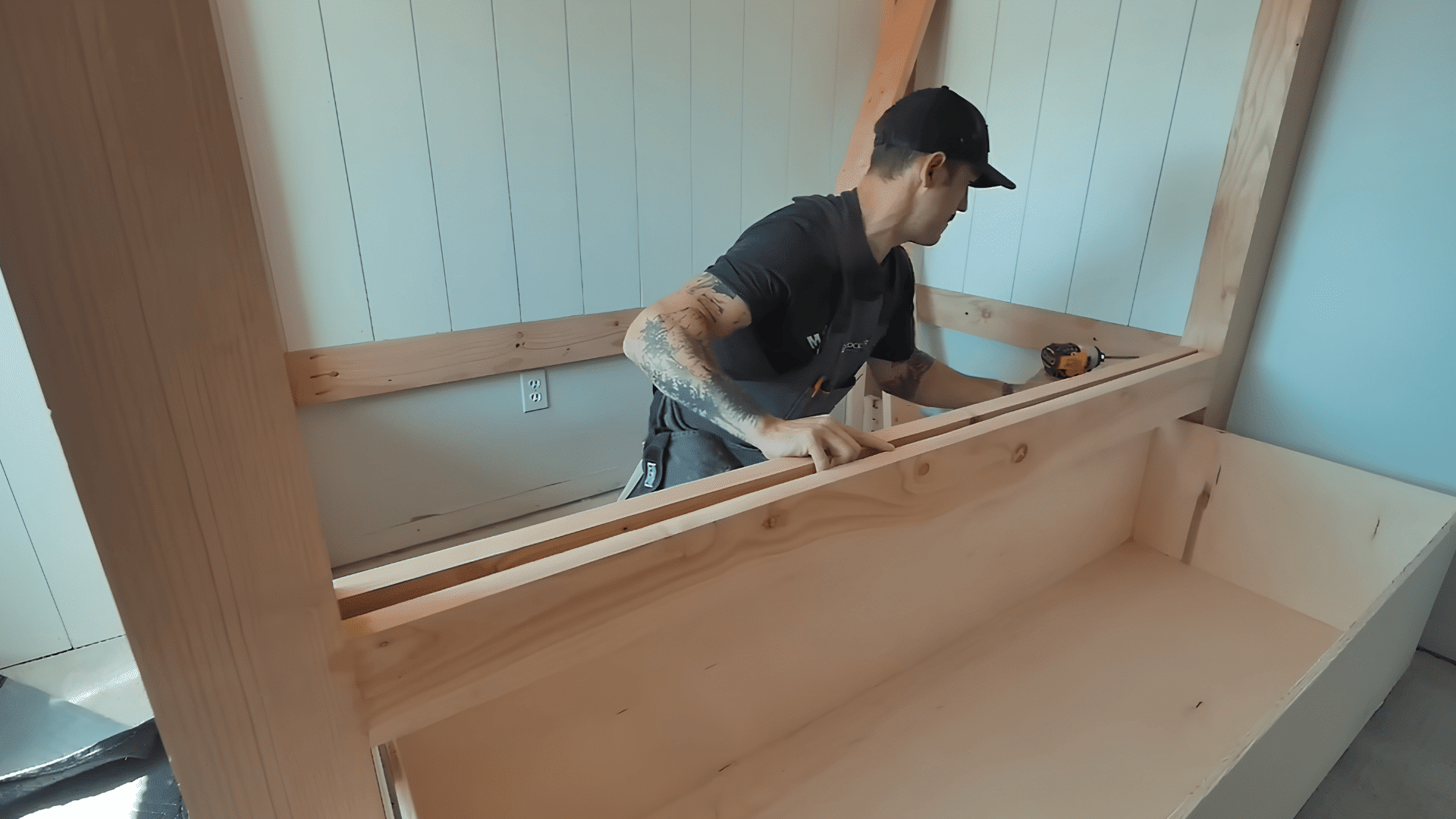 man assembling the wooden frame and support rails for a full-size built-in bunk bed