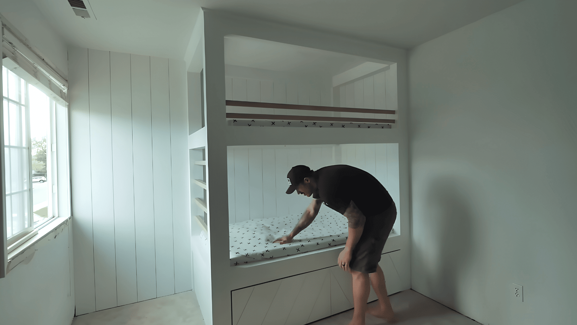 man measuring a wall and floor area while planning a full-size built-in bunk bed frame