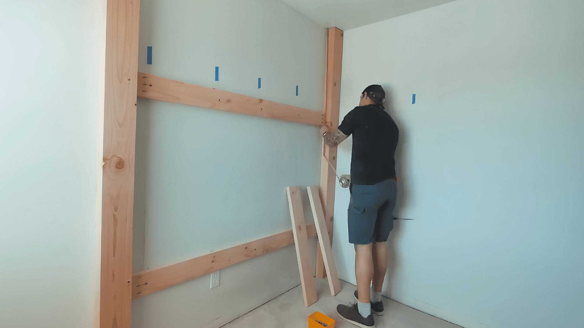 man painting the built-in bunk bed frame white while protecting nearby walls and floors