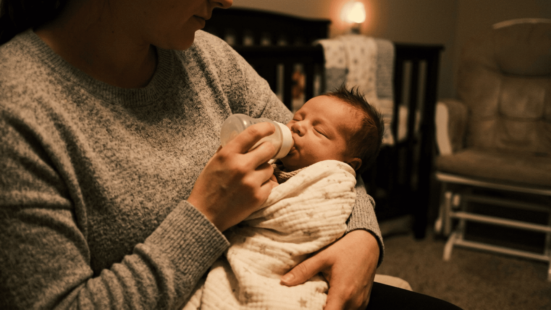 mother bottle-feeding her sleepy baby during a nighttime dream feed