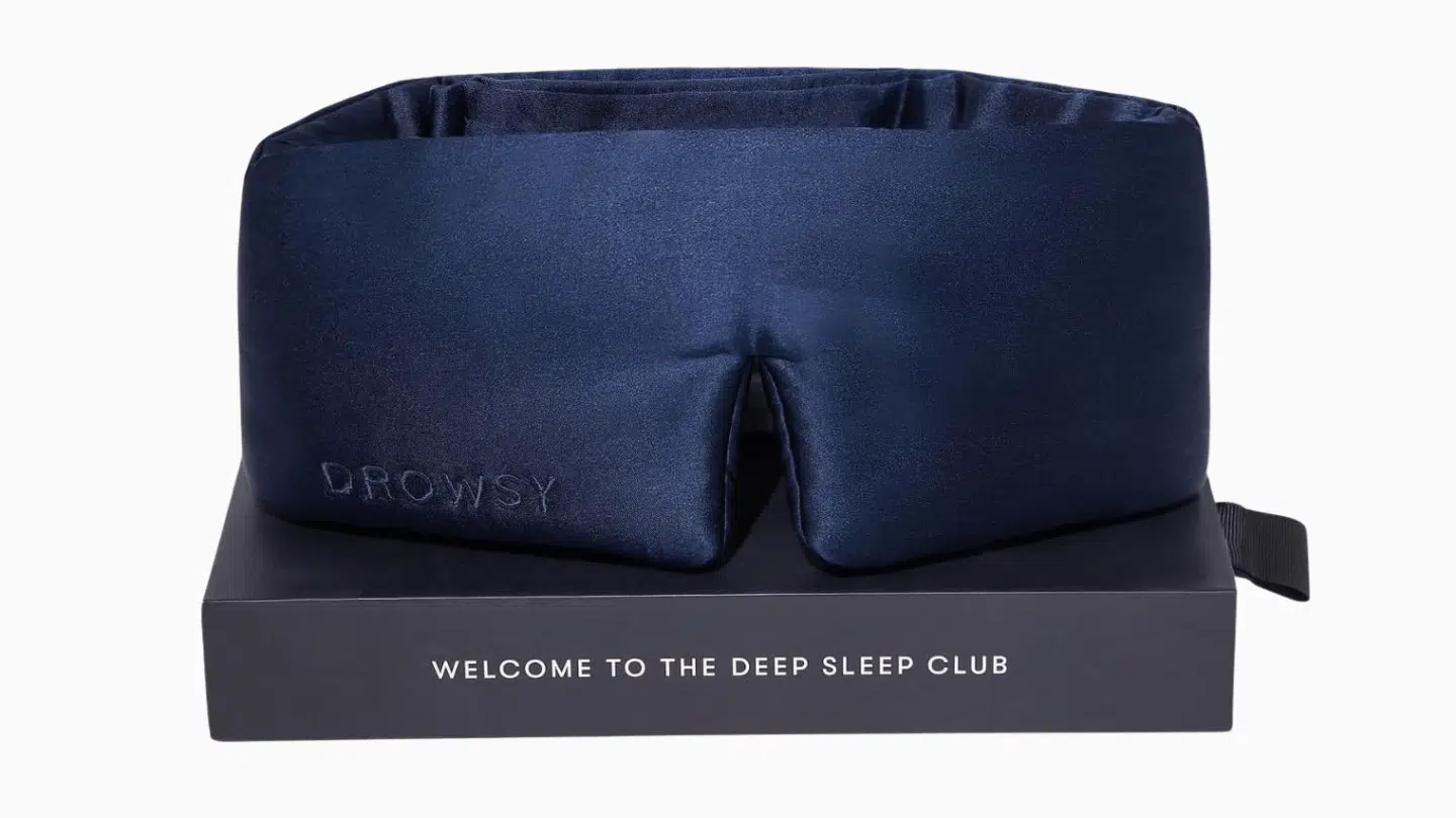 navy Drowsy padded silk sleep mask with wide wrap-around band displayed on its dark presentation box