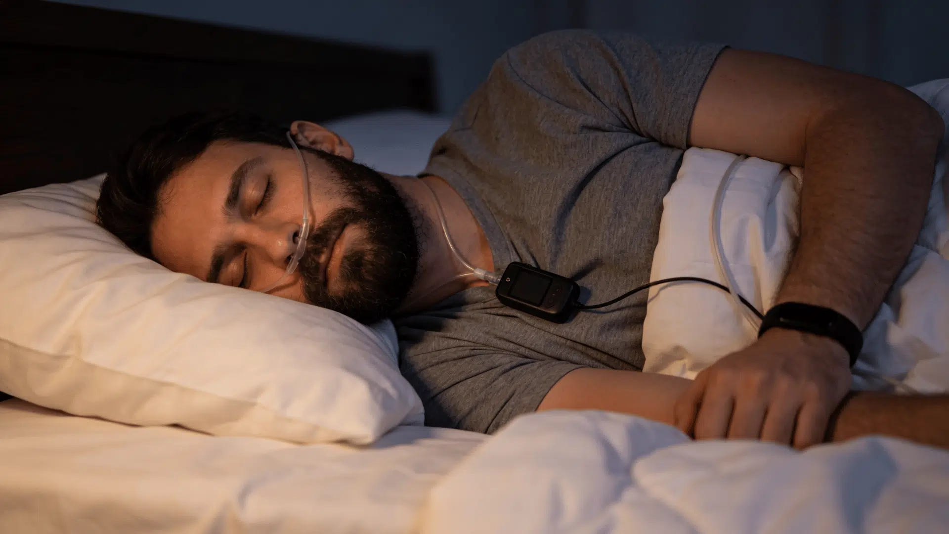 Person wearing a home sleep study device with nasal tube while sleeping in bed