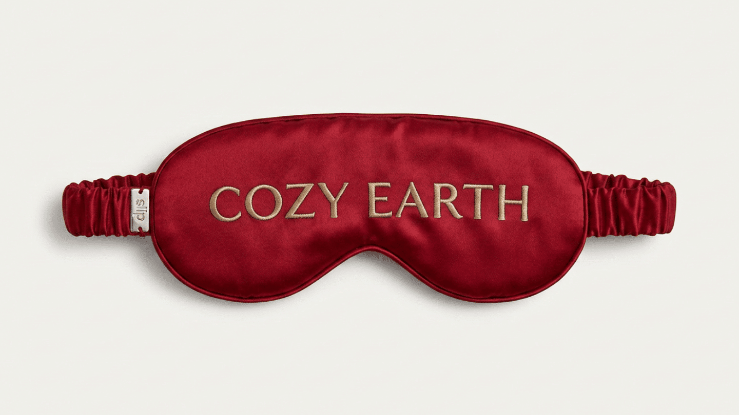 red Cozy Earth silk sleep mask with embroidered branding and a covered elastic head strap on display