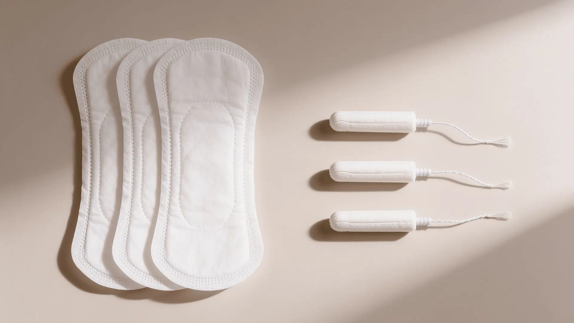 sanitary pads and tampons arranged side by side on a neutral background
