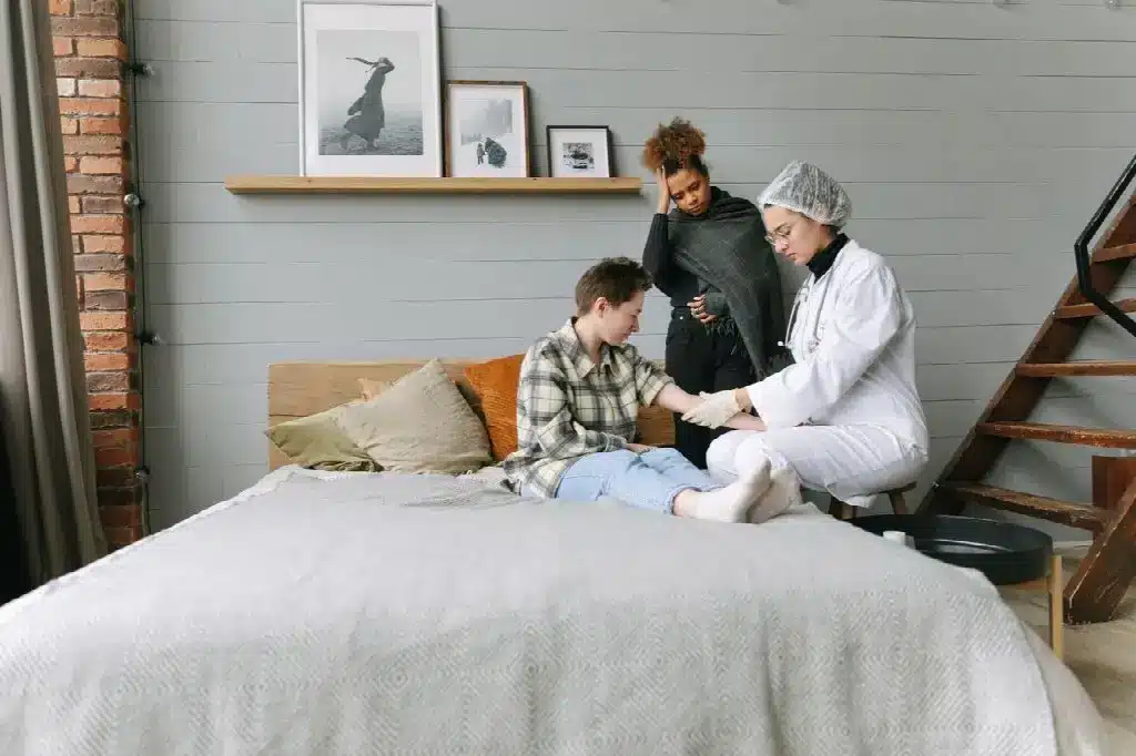 Person receiving medical attention on bed in cozy room with framed photos and wooden ladder